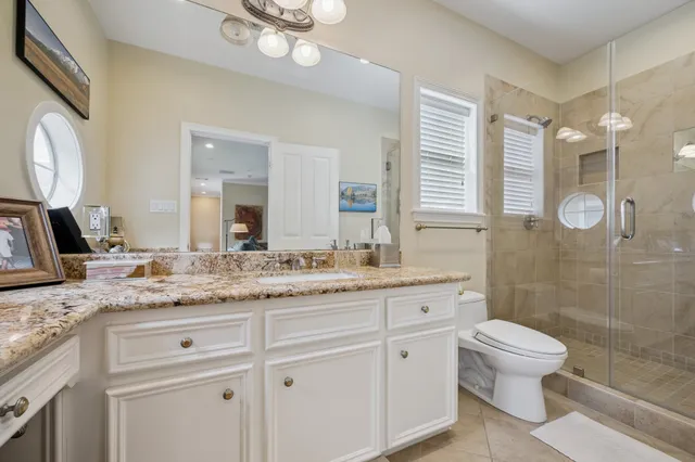 a bathroom with a granite countertop sink a toilet a mirror and shower