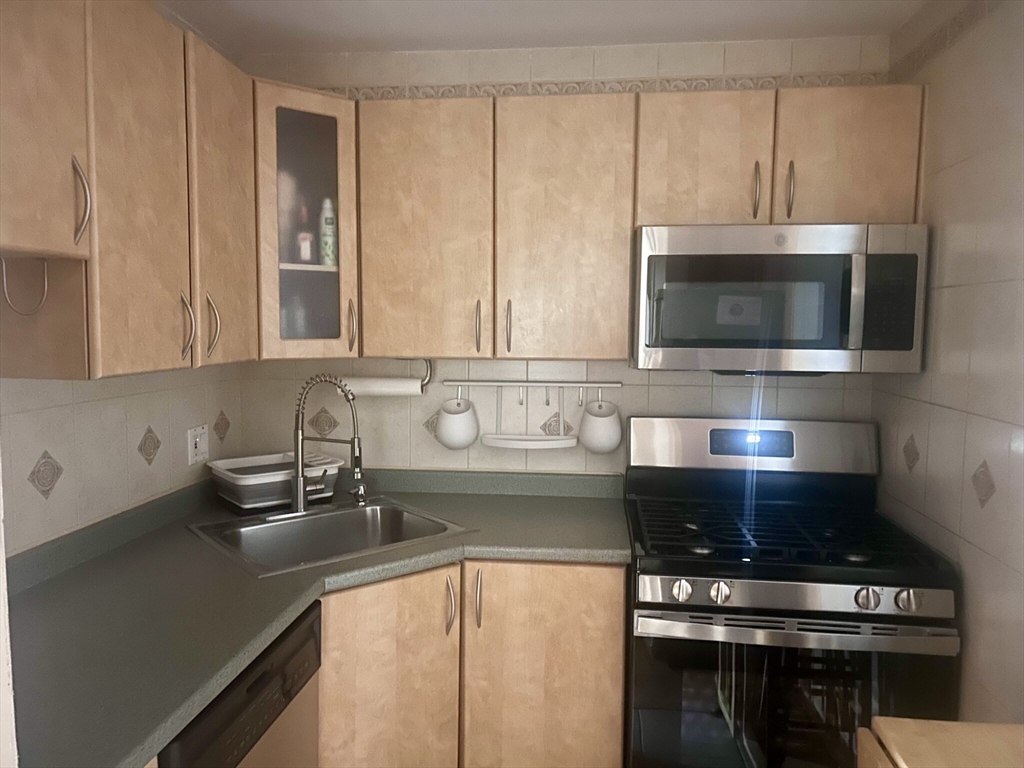 140 Kenrick Street, Unit 21 Boston, MA 02135 - Photo 4 of 36 a kitchen with stainless steel appliances a stove a microwave and cabinets