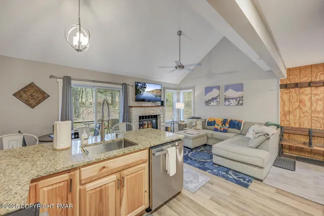 a living room with granite countertop furniture a fireplace a flat screen tv and windows