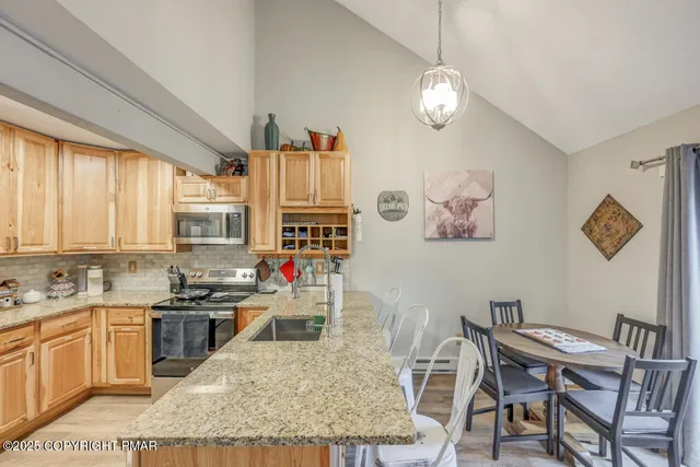 a kitchen with kitchen island granite countertop a stove a sink a dining table and chairs with wooden floor