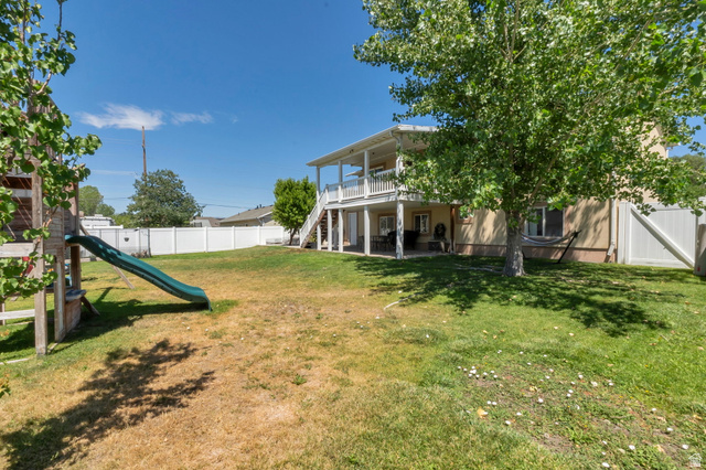 2013 West 460 South Provo, UT 84601 - Photo 23 of 24 Expansive backyard featuring a two-story exterior with a second-level balcony, covered patio, and white privacy fencing