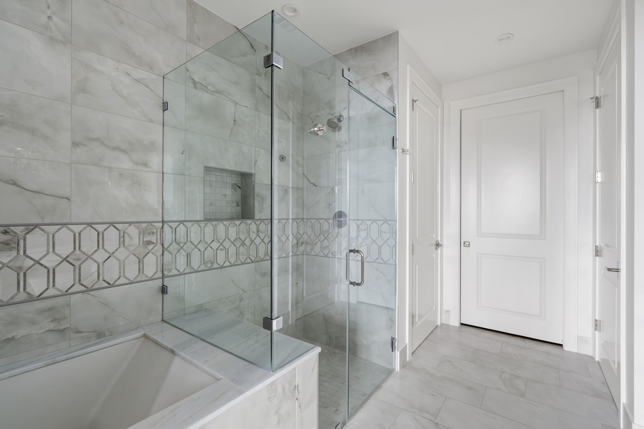 5656 San Felipe Street, Unit 1401 Houston, TX 77056 - Photo 21 of 40 This elegant bathroom features a spacious dual-sink vanity, tile flooring, and a glass-enclosed shower and separate soaking tub. Crystal chandeliers add a touch of luxury, while the large mirror enhances the bright, airy feel.