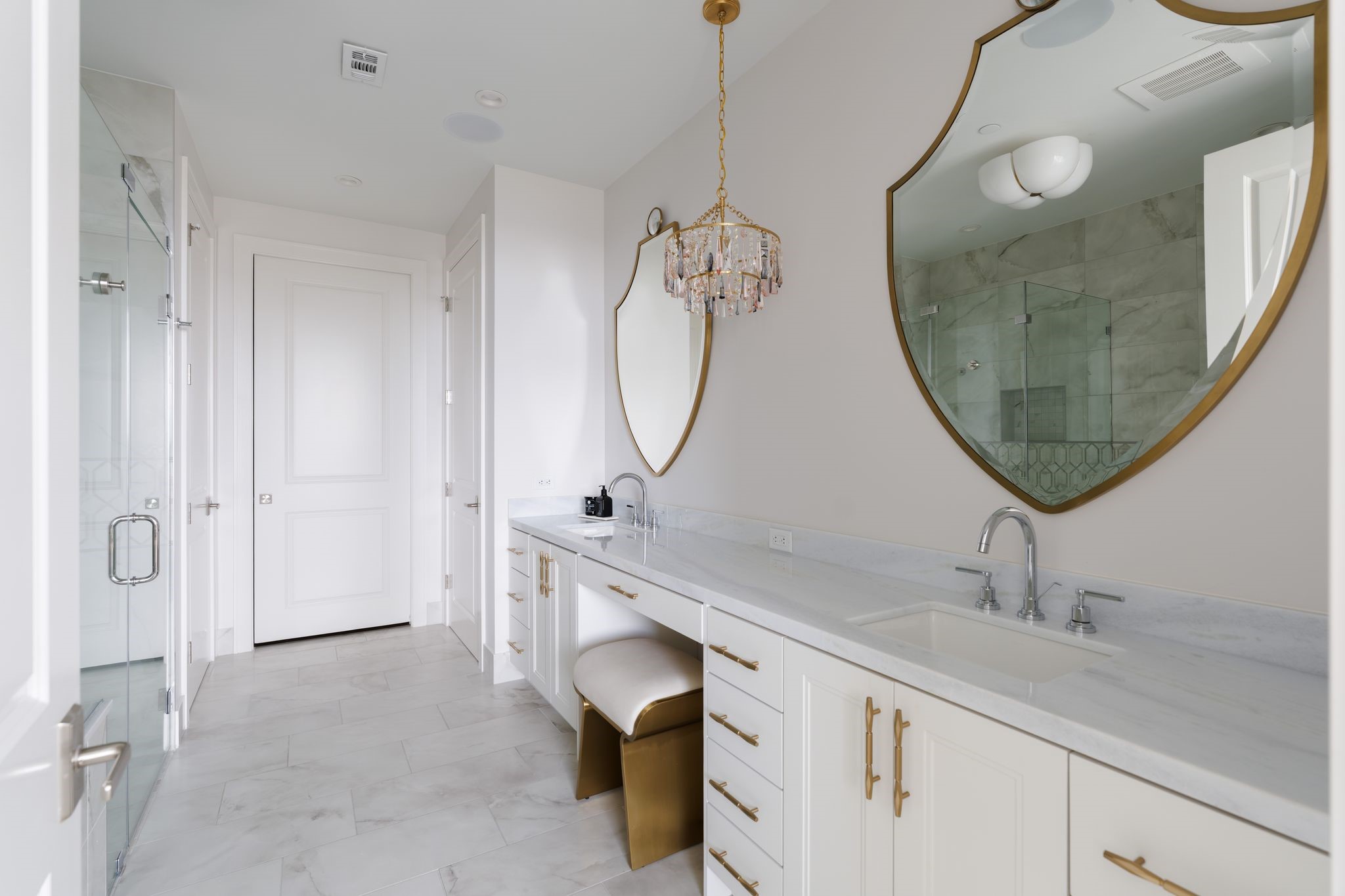 5656 San Felipe Street, Unit 1401 Houston, TX 77056 - Photo 25 of 40 This elegant bathroom features a spacious dual-sink vanity, tile flooring, and a glass-enclosed shower and separate soaking tub. Crystal chandeliers add a touch of luxury, while the large mirror enhances the bright, airy feel.