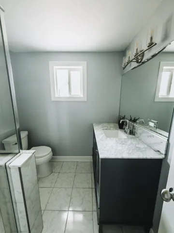a bathroom with a granite countertop sink a toilet and a mirror