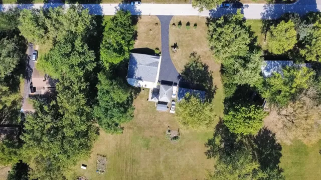 an aerial view of residential house with outdoor space and trees all around