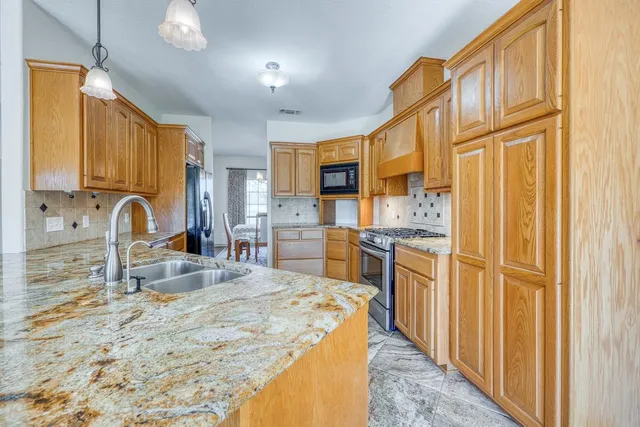 a kitchen with stainless steel appliances granite countertop a sink a stove and a refrigerator
