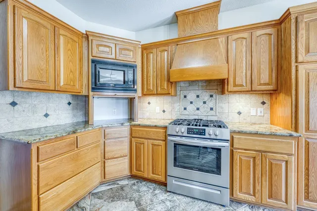 a kitchen with granite countertop a stove top oven microwave and cabinets