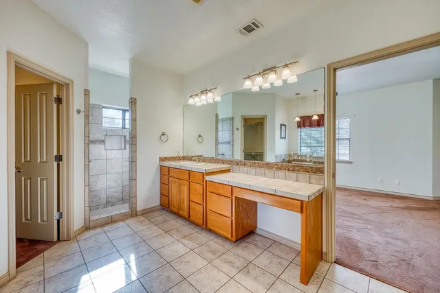 a spacious bathroom with a granite countertop sink a mirror and a shower