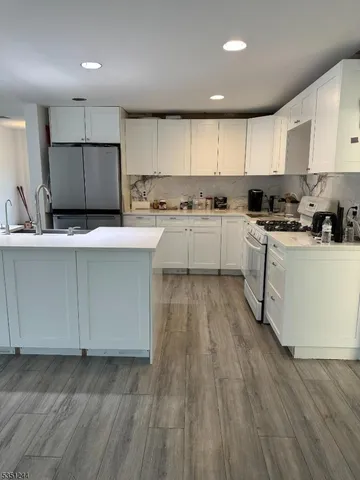 a kitchen with wooden floors white cabinets and stainless steel appliances