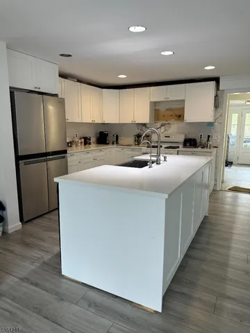 a kitchen with stainless steel appliances a refrigerator a sink a stove top oven a wooden floor and cabinets