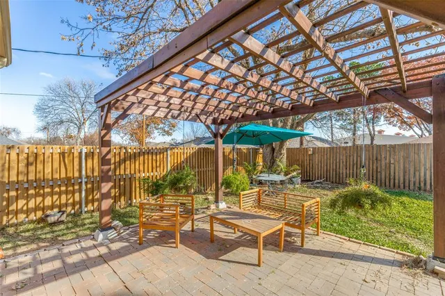 a view of patio with table and chairs under an umbrella with a small yard