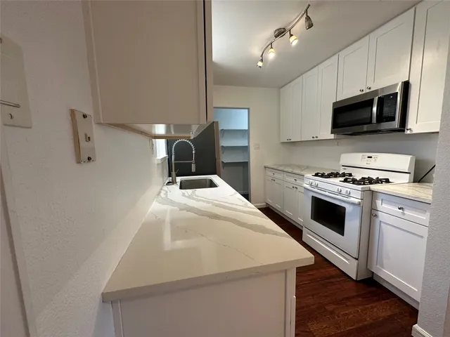 a kitchen with stainless steel appliances a stove a microwave and white cabinets