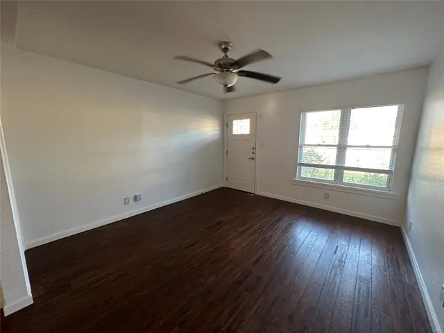 an empty room with wooden floor fan and windows