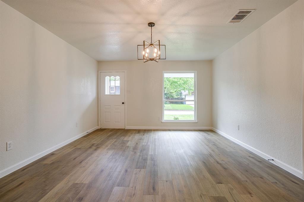 713 Vaughn Drive Burleson, TX 76028 - Photo 11 of 40 an empty room with wooden floor chandelier and windows