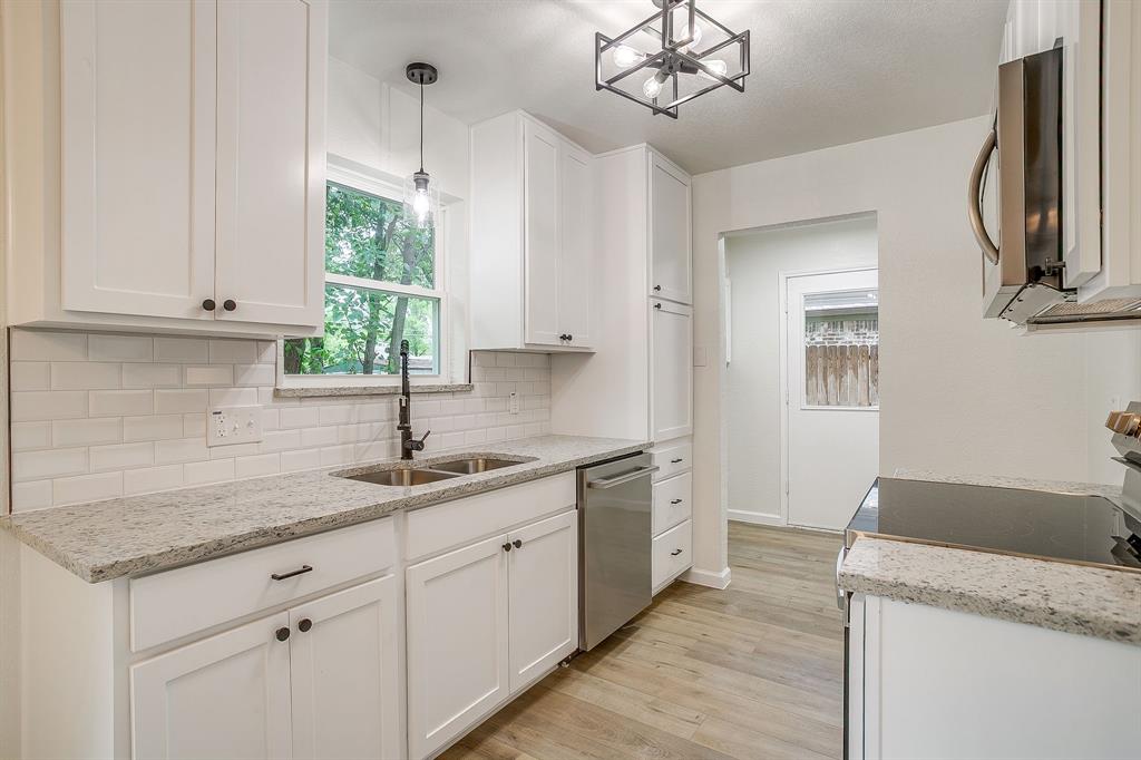 713 Vaughn Drive Burleson, TX 76028 - Photo 20 of 40 a kitchen with a sink dishwasher a stove and white cabinets with wooden floor