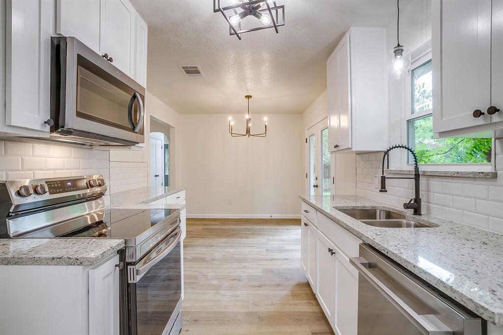 713 Vaughn Drive Burleson, TX 76028 - Photo 22 of 40 a kitchen with stainless steel appliances granite countertop a sink a stove and a wooden cabinets