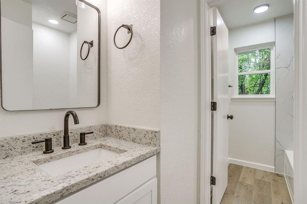 713 Vaughn Drive Burleson, TX 76028 - Photo 25 of 40 a bathroom with a granite countertop sink and a mirror