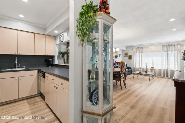 a kitchen with stainless steel appliances granite countertop a refrigerator a stove a sink a dining table and chairs with wooden floor