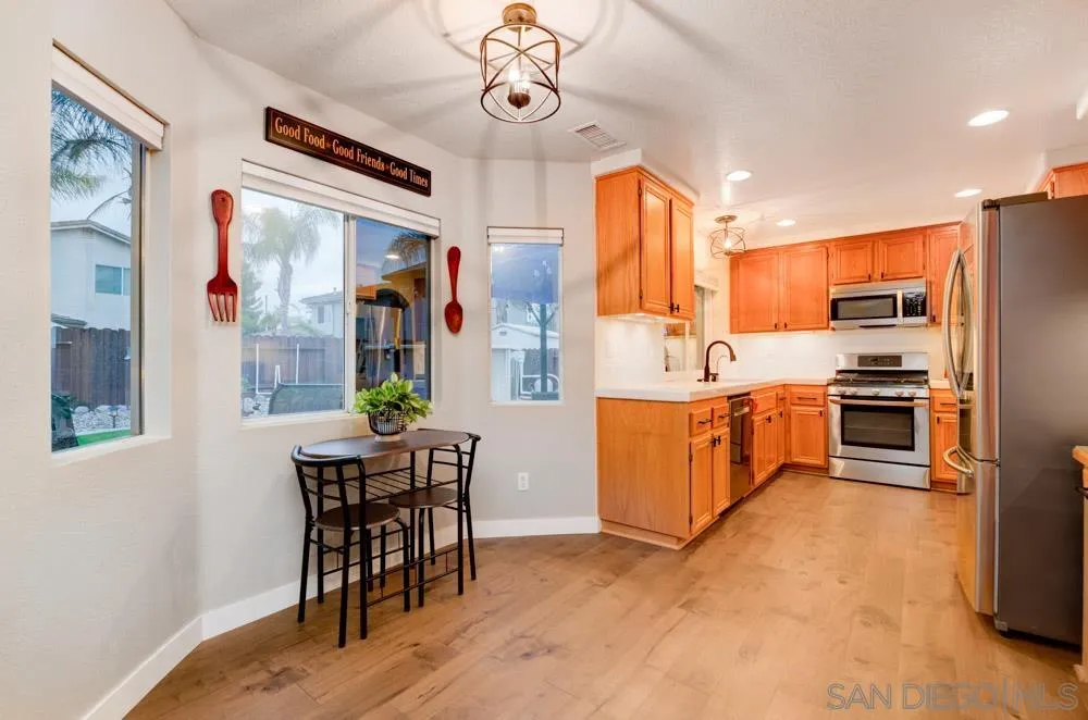 10205 Pinon Place Lakeside, CA 92040 - Photo 7 of 23 a kitchen with stainless steel appliances kitchen island granite countertop a table chairs in it and wooden floors