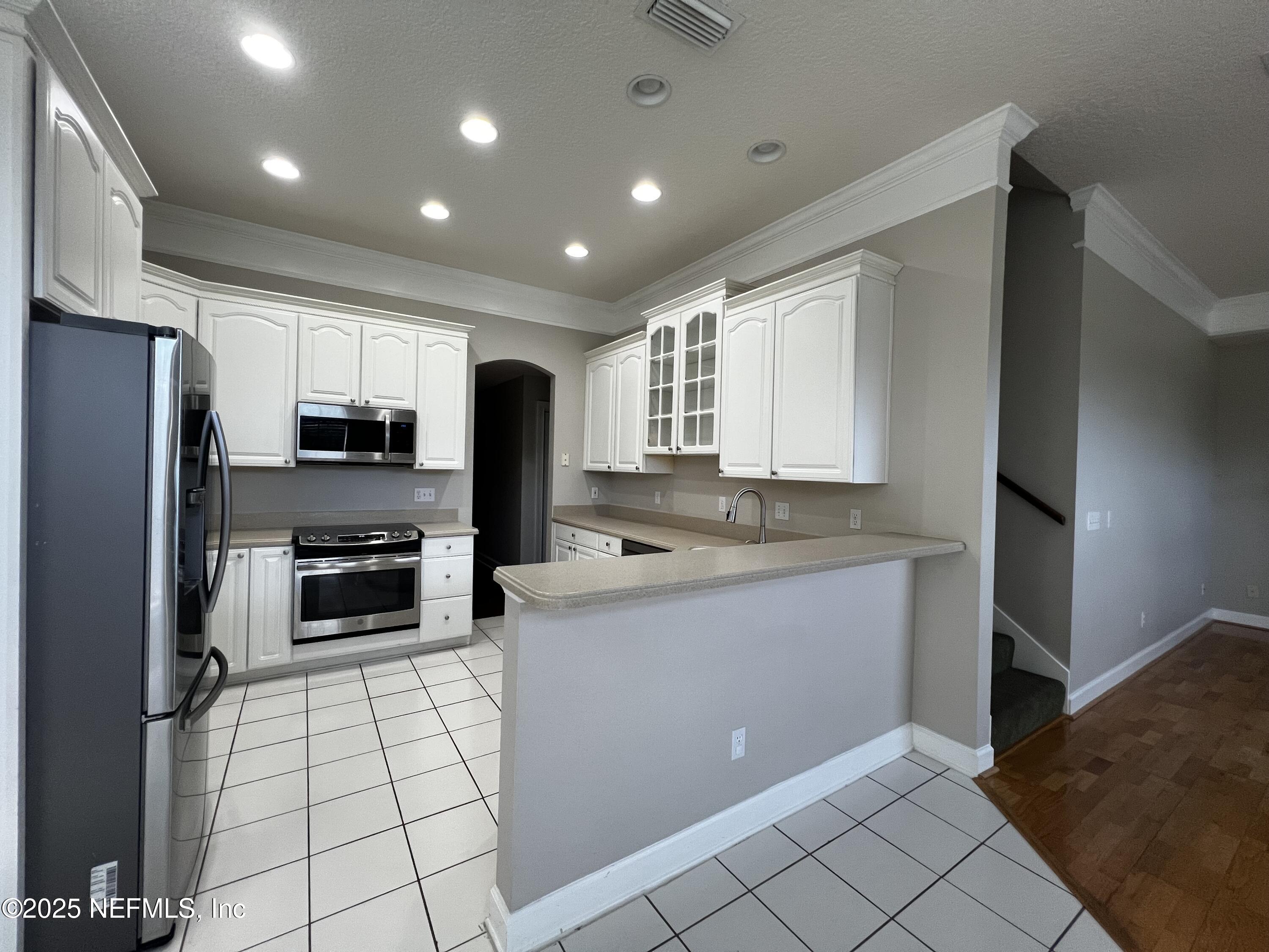 10310 Hamlet Glen Drive Jacksonville, FL 32221 - Photo 12 of 33 a kitchen with stainless steel appliances a refrigerator sink stove microwave and cabinets