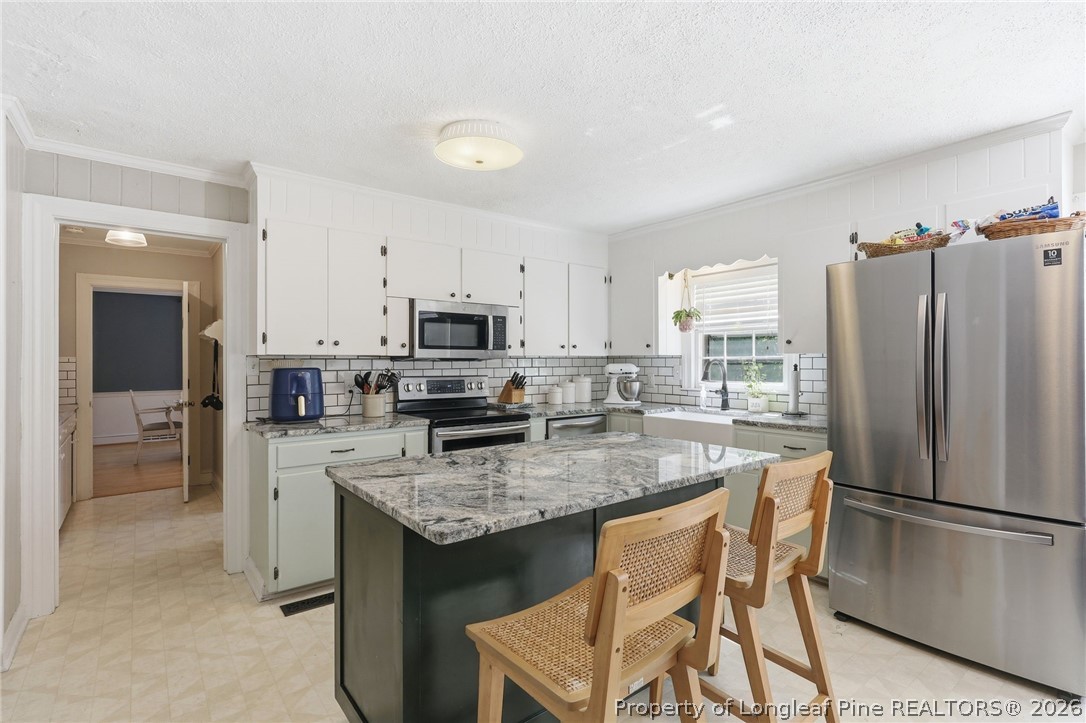 1322 Carolina Drive Rockingham, NC 28379 - Photo 10 of 28 a kitchen with stainless steel appliances granite countertop a table chairs microwave and refrigerator