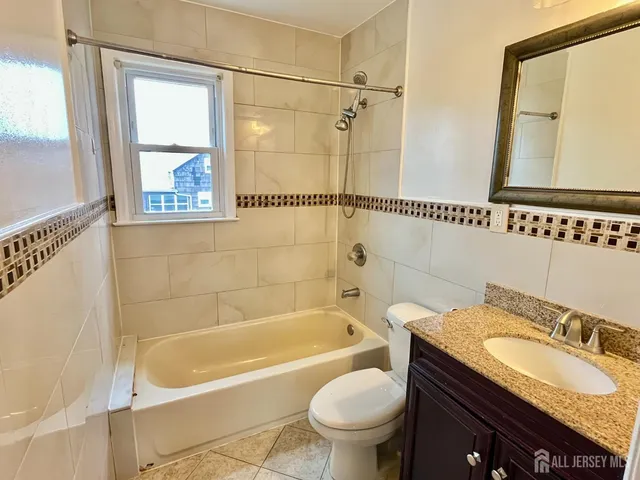 a bathroom with a granite countertop sink mirror toilet and bathtub
