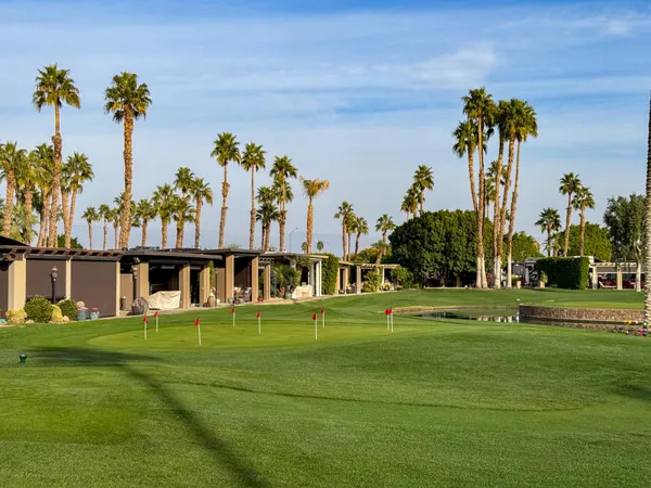 a view of a white house with a big yard and palm trees