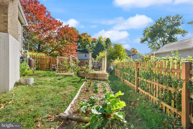 a view of empty room with wooden floor and kitchen