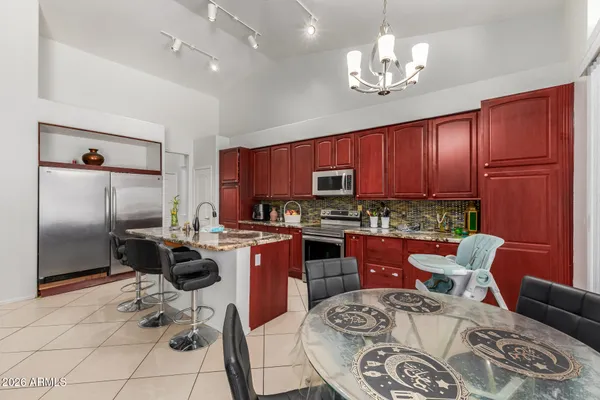 a kitchen with stainless steel appliances granite countertop a stove top oven a refrigerator a sink dishwasher a dining table and chairs with wooden floor