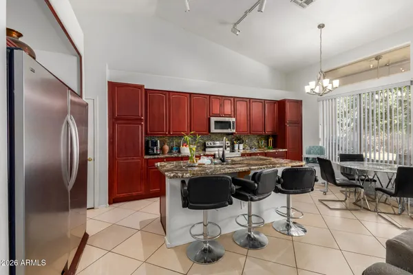 a kitchen with stainless steel appliances kitchen island granite countertop a refrigerator a stove a sink dishwasher and a dining table with wooden floor
