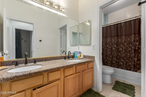a bathroom with a granite countertop sink a toilet a mirror and shower curtain