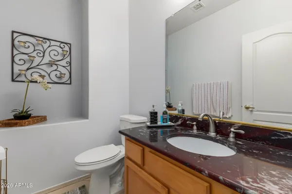 a bathroom with a granite countertop sink mirror vanity and toilet