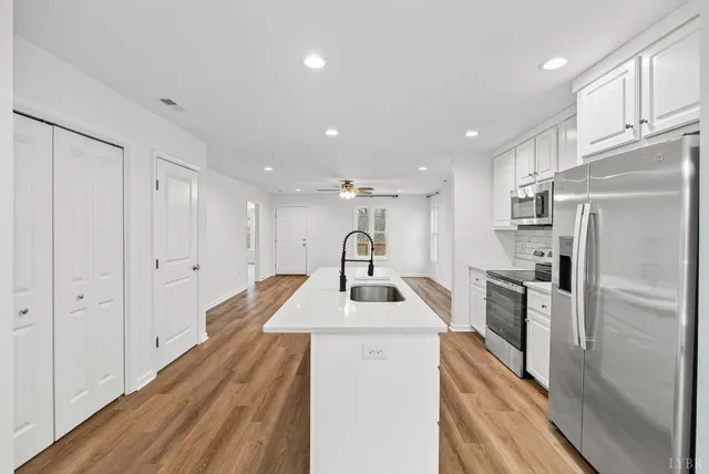 a kitchen with kitchen island a counter top space a sink stainless steel appliances and cabinets