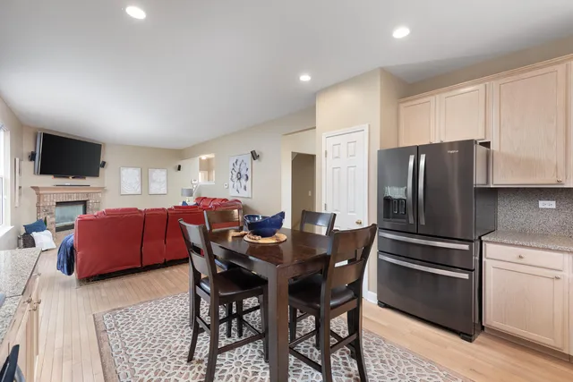 a kitchen with stainless steel appliances granite countertop a refrigerator a stove a sink dishwasher a dining table and chairs with wooden floor