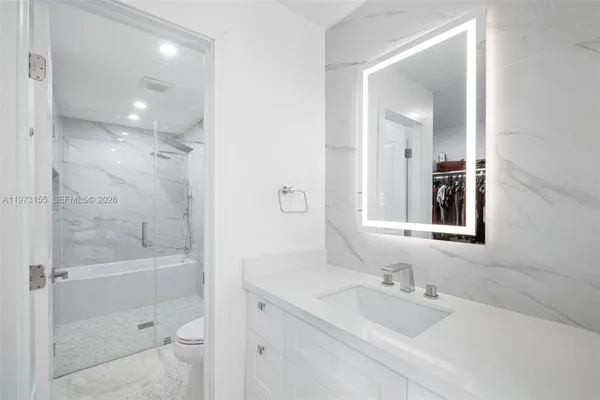 a bathroom with a bathtub shower sink vanity and mirror