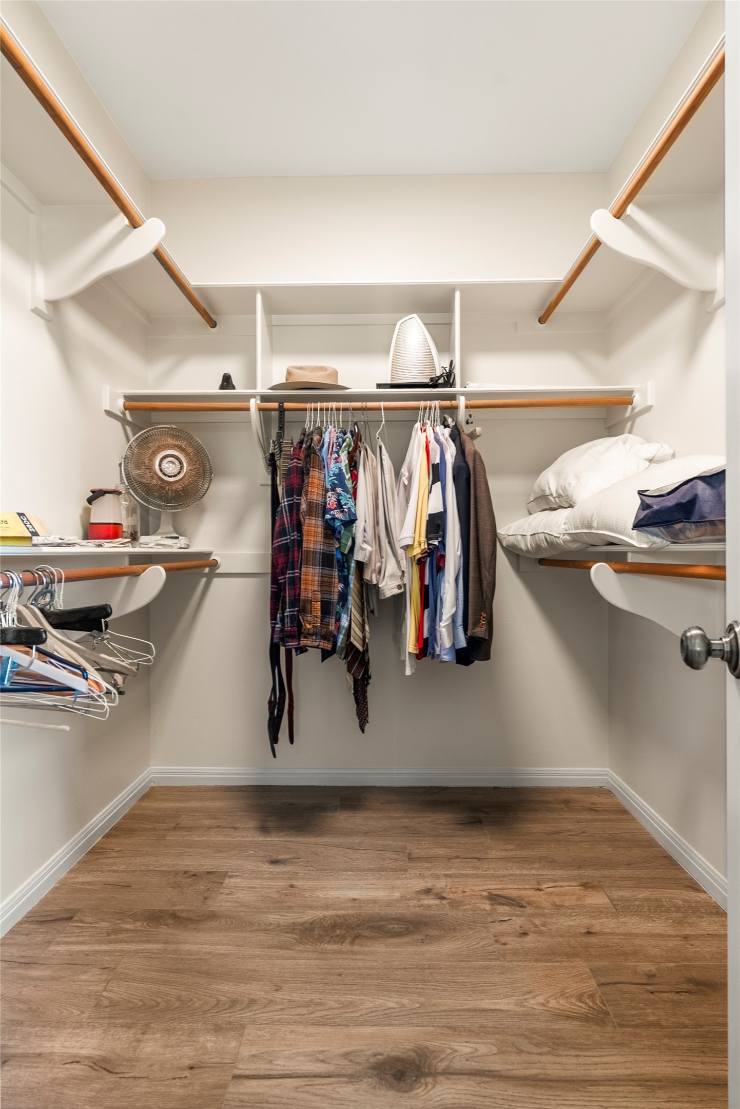928 Upper Elgin River Road Elgin, TX 78621 - Photo 22 of 40 Walk-in closet featuring wood-finish flooring, white built-in shelving, multiple hanging rods, and white baseboards.