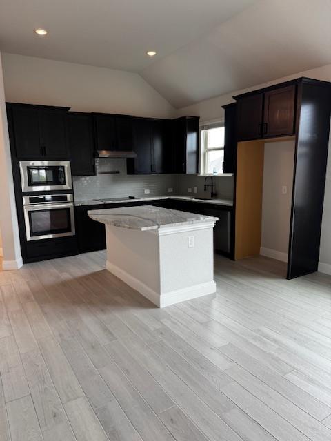 1432 Ridge Runner Drive Georgetown, TX 78628 - Photo 8 of 27 Kitchen featuring a kitchen island, stainless steel appliances, light wood-style flooring, dark cabinets, and lofted ceiling