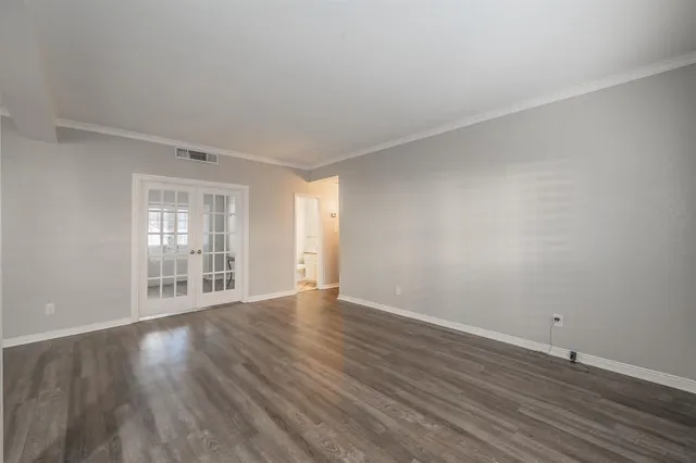 a view of an empty room with wooden floor and windows