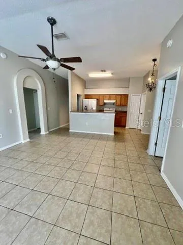 a view of a refrigerator in kitchen and an empty room