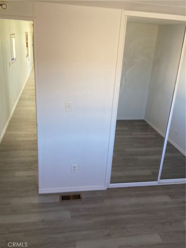 6376 Coyote Road Phelan, CA 92371 - Photo 13 of 19 a view of an empty room with wooden floor and a hallway