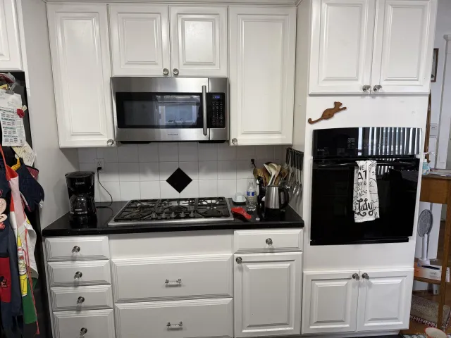 a kitchen with white cabinets and black appliances