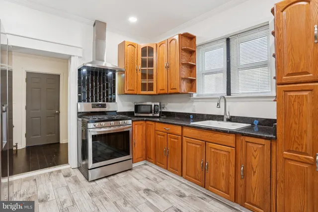 a kitchen with stainless steel appliances granite countertop a sink and a stove next to a window