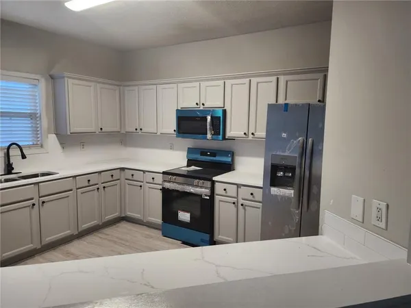 a kitchen with granite countertop a refrigerator stove and sink