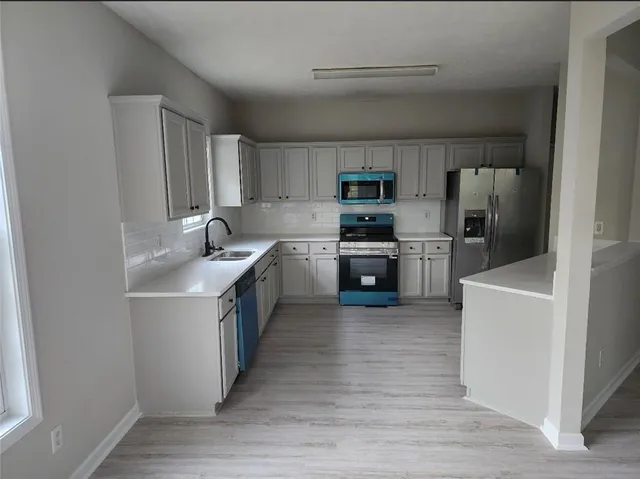 a kitchen with stainless steel appliances granite countertop a sink stove refrigerator and cabinets