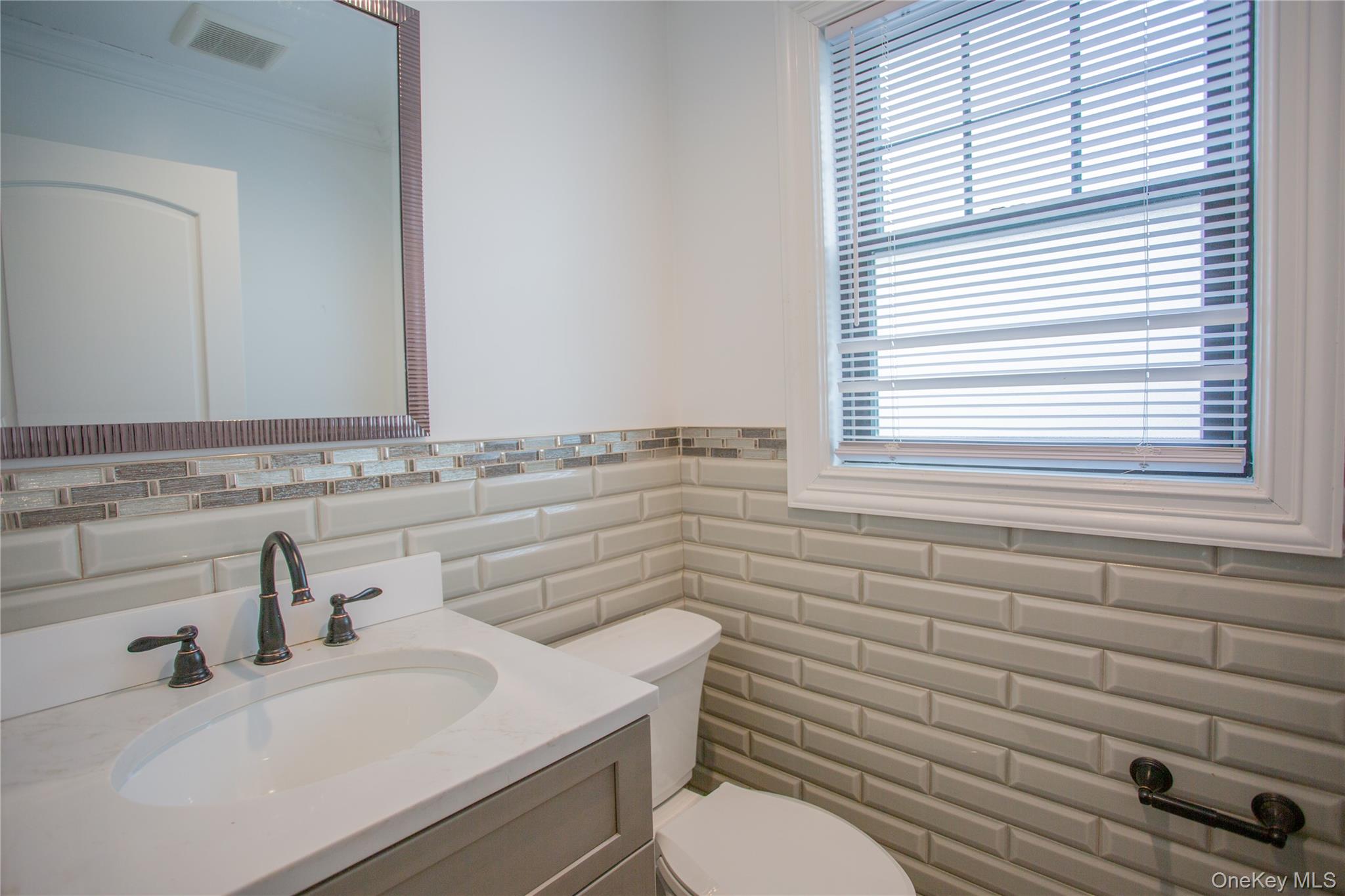 59 Clinton Avenue Inwood, NY 11096 - Photo 8 of 19 a bathroom with a sink a toilet and a mirror