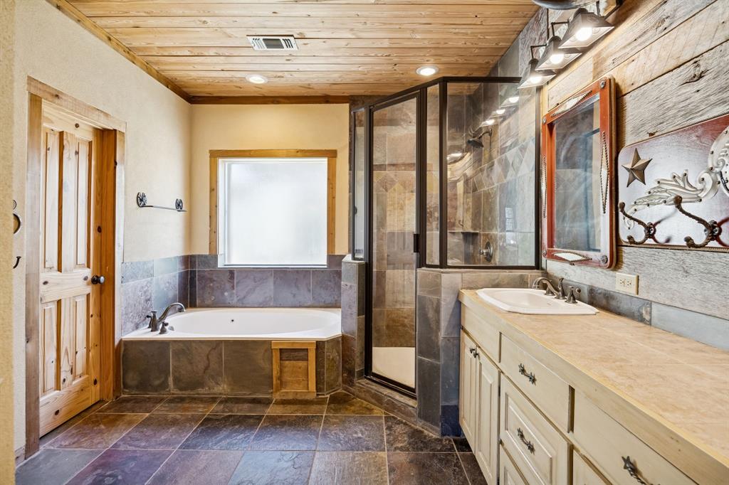 1922 A Bethel-Cannon Road Whitewright, TX 75491 - Photo 15 of 40 Bathroom featuring a wood-panel ceiling, stone tile flooring, and a glass-enclosed shower