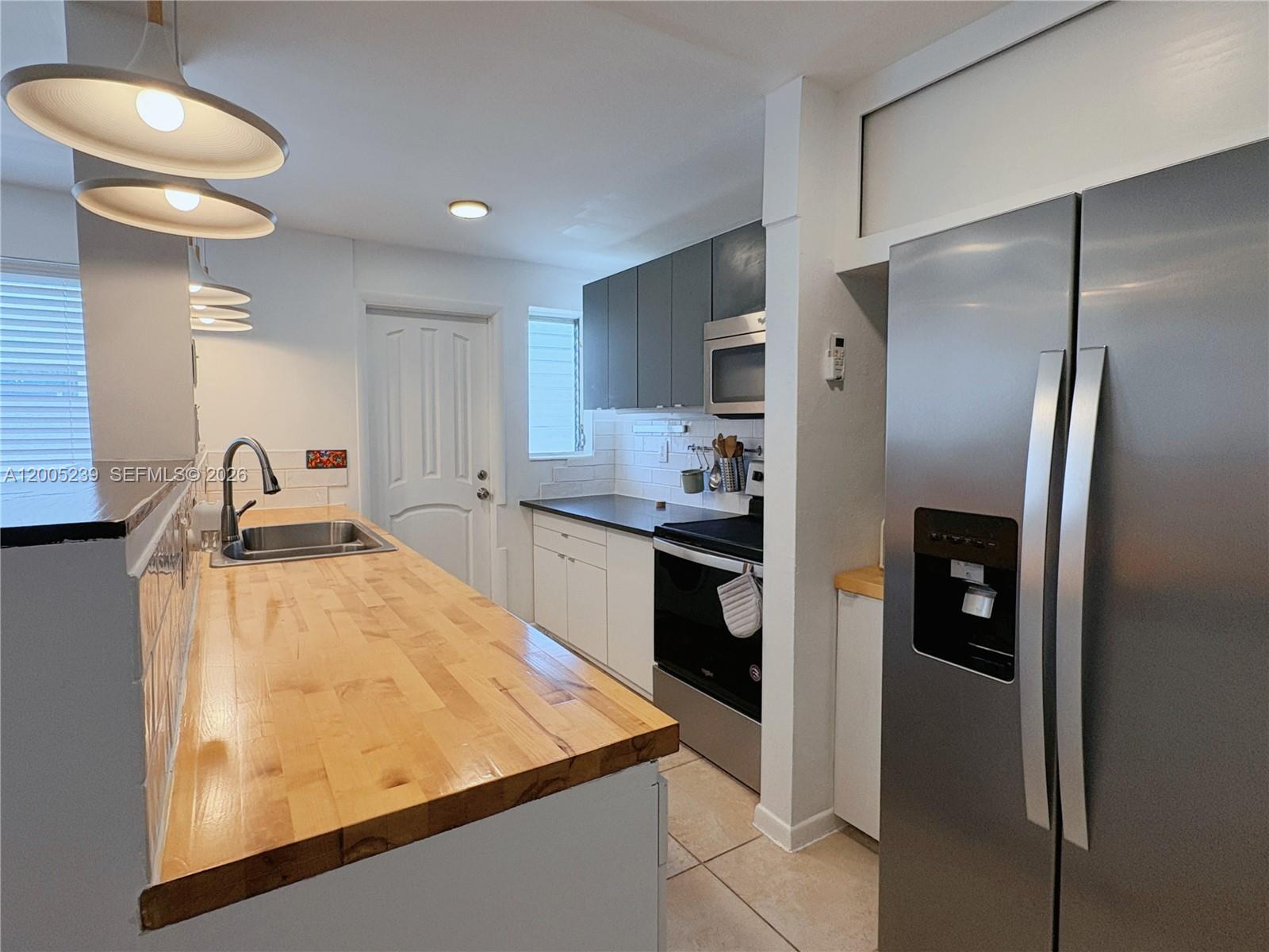 944 Meridian Avenue, Unit 11 Miami Beach, FL 33139 - Photo 6 of 14 a kitchen with stainless steel appliances granite countertop a refrigerator a sink and a stove