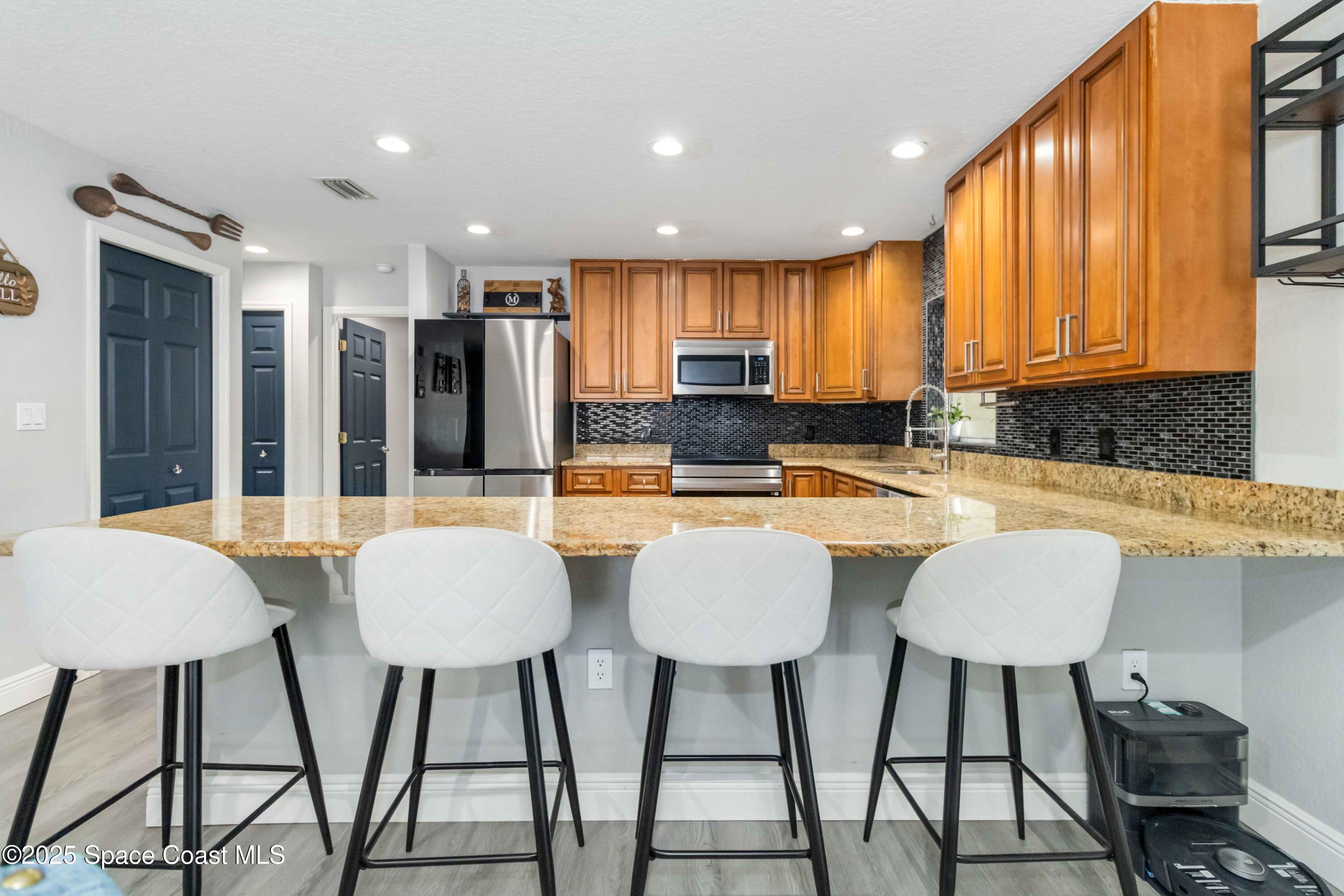 1149 Scyphers Street Northeast Palm Bay, FL 32905 - Photo 18 of 39 a kitchen with stainless steel appliances kitchen island granite countertop a dining table chairs and a sink