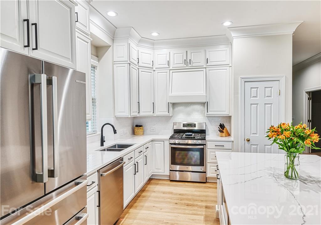 1380 Barnett Woods Fort Mill, SC 29708 - Photo 7 of 31 a kitchen with stainless steel appliances kitchen island granite countertop a refrigerator a sink dishwasher and white cabinets with wooden floor