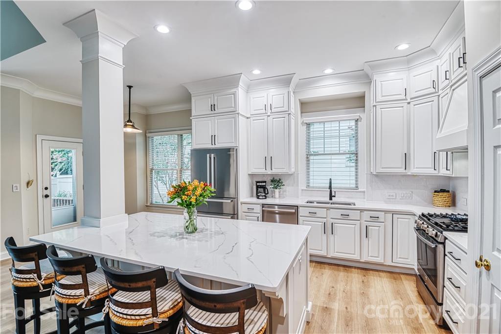 1380 Barnett Woods Fort Mill, SC 29708 - Photo 8 of 31 a kitchen with stainless steel appliances kitchen island granite countertop a table chairs in it and wooden floors